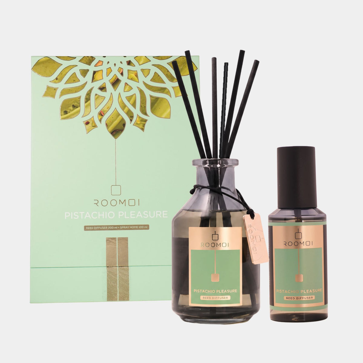 ROOMOI Pistachio Pleasure reed diffuser set featuring a large glass reed diffuser bottle with black reeds, a smaller matching bottle, and the mint green and gold outer packaging box, all on a light gray background.
